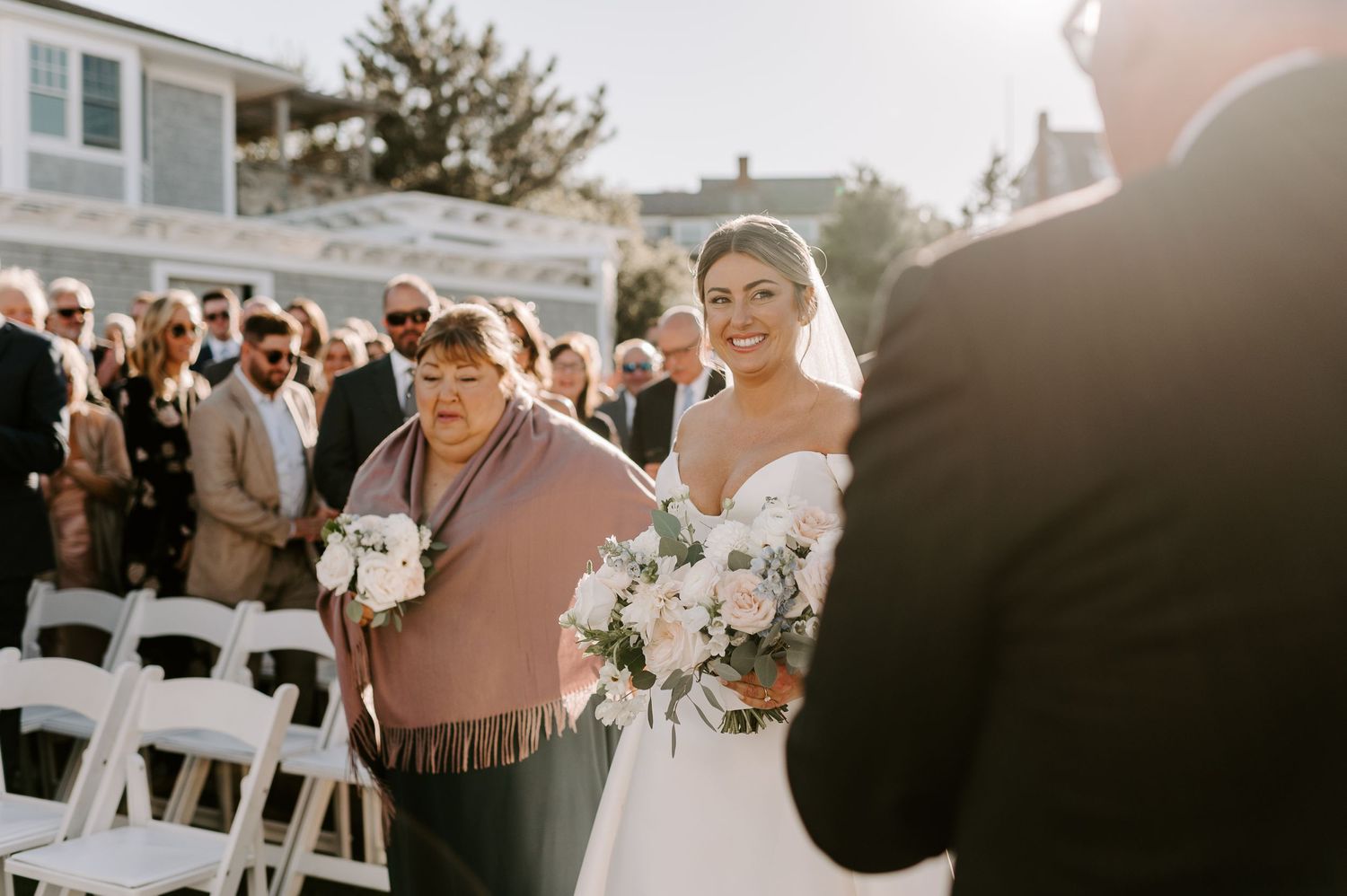 Wedding guests gathering at an outdoor reception venue near the beach.