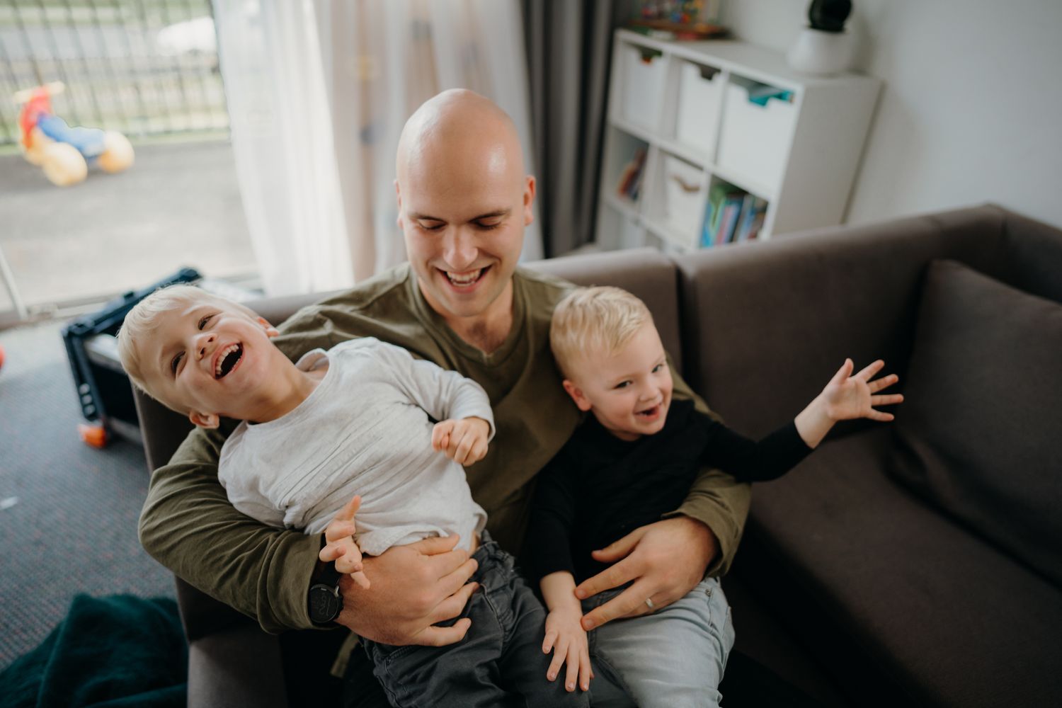 dad tickling twin boys while on the couch during a lifestyle family shoot