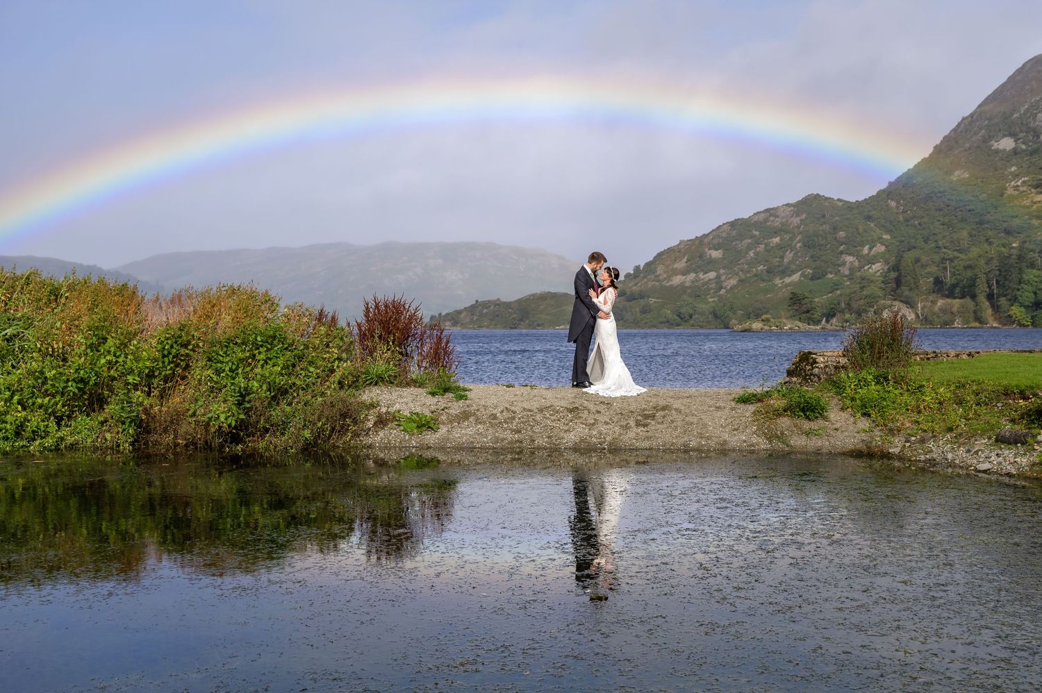 Bride and groom by pool with rainbow at Inn on the Lake wedding
