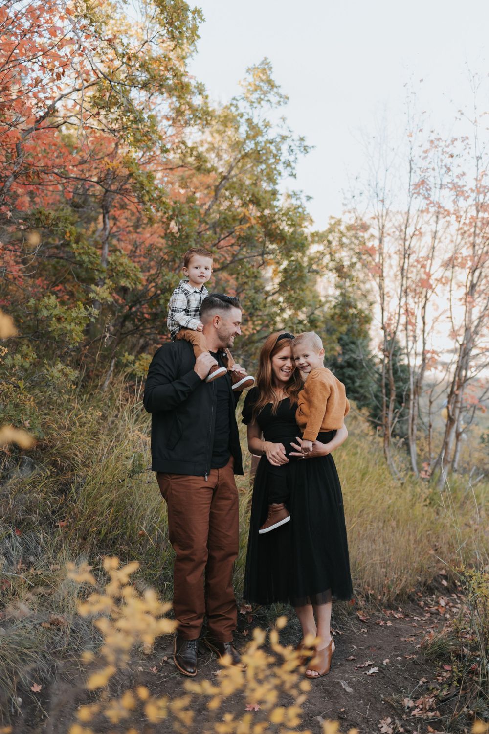 A family poses in the fall foliage for family photos with a talented local family photographer in Alpine, Utah.