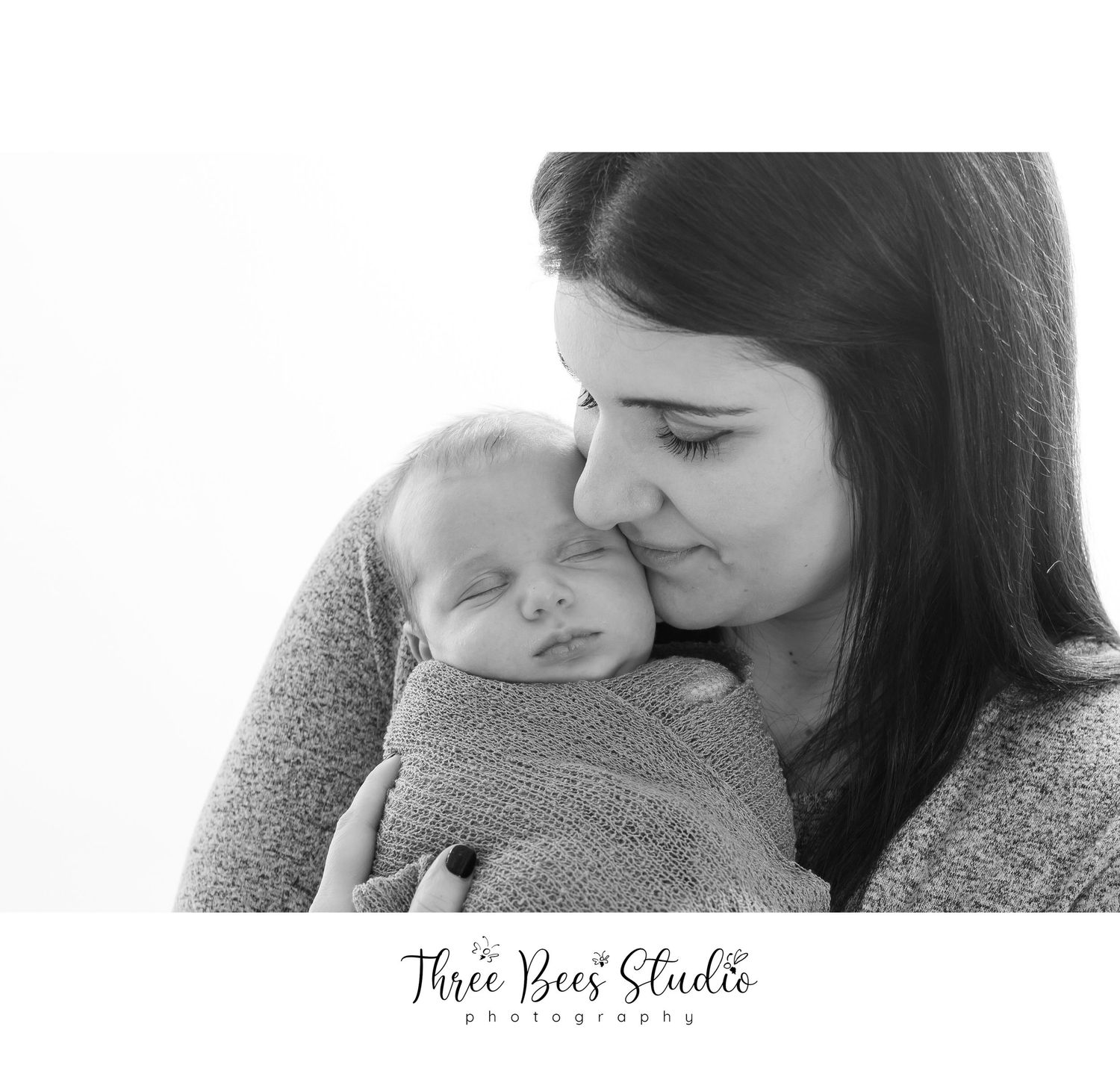 Black and white intimate portrait of tender moment during newborn photography session.