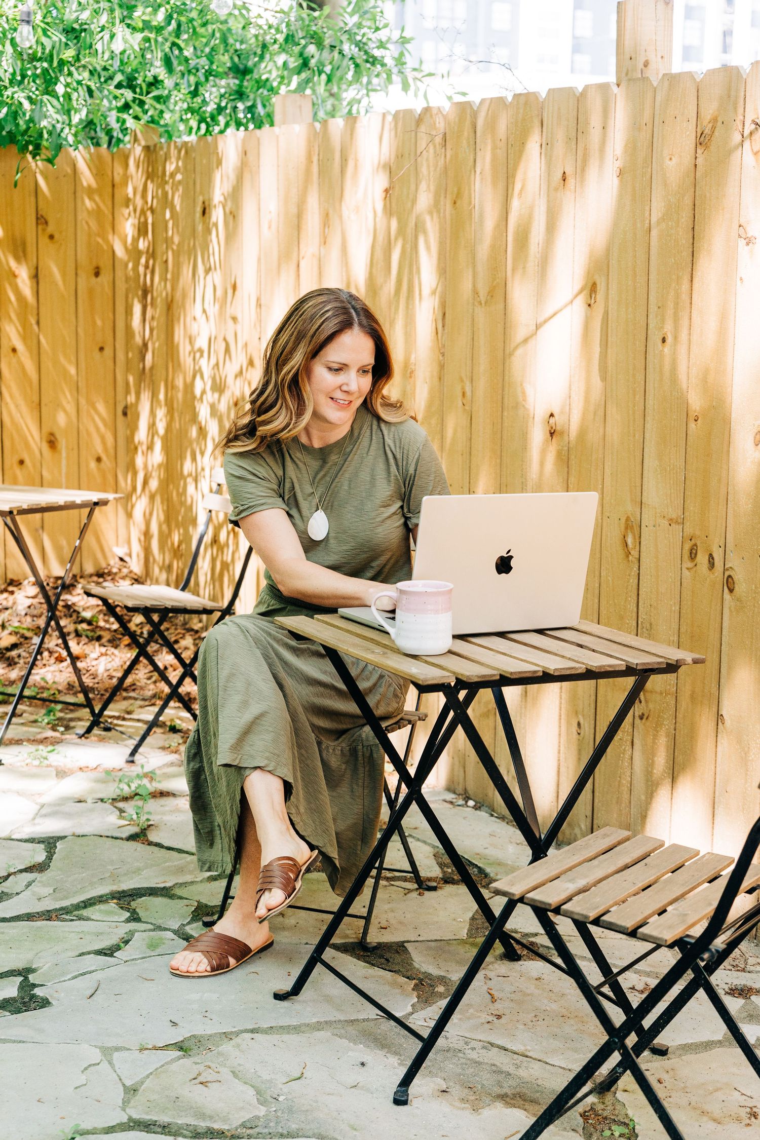 brand photographer sitting outside for her own branding photos with her laptop and coffee at Little Villa Charlotte
