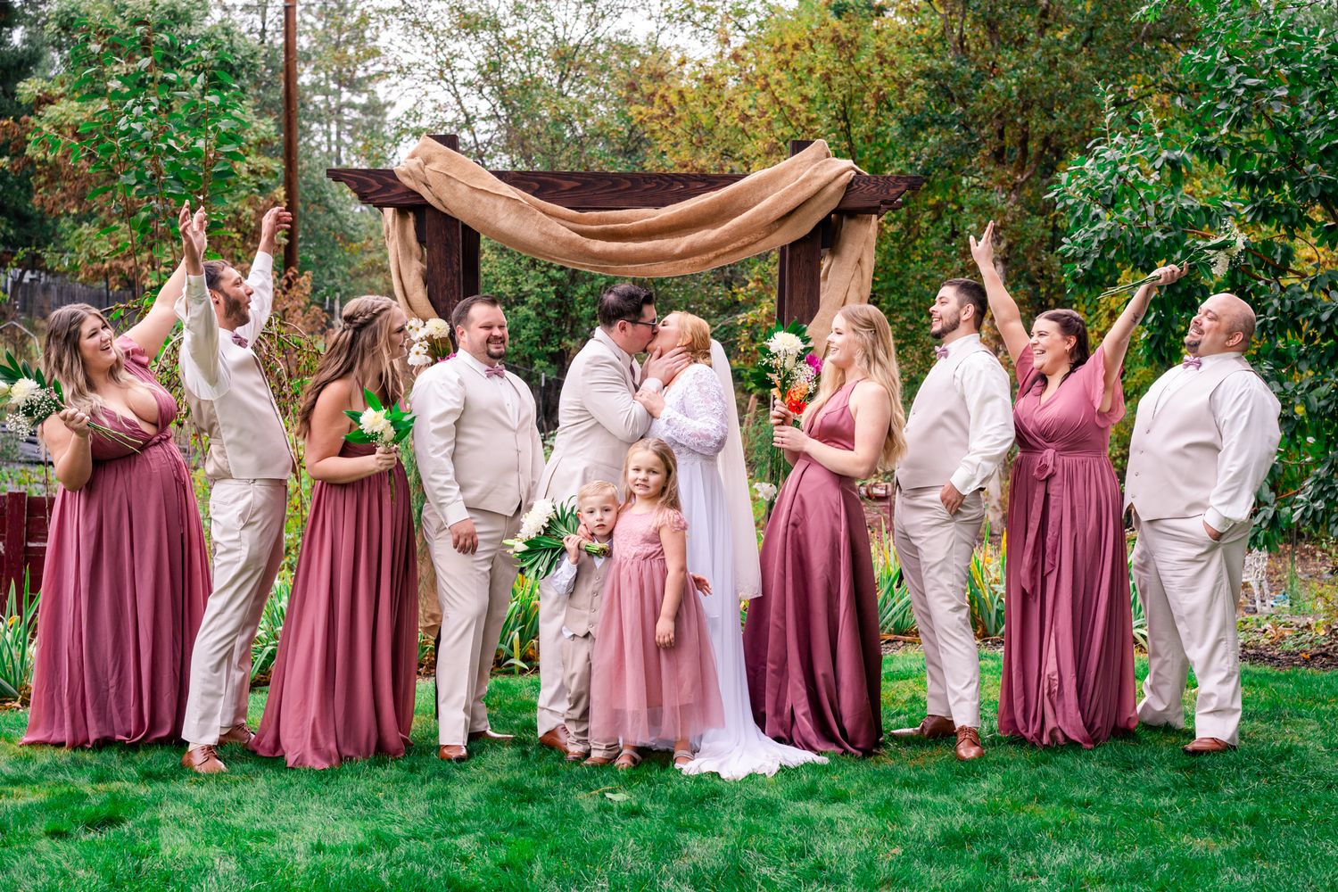 bridal party cheers while bride and groom kiss