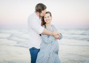 Romantic beach portraits showing couple embracing by the ocean.
