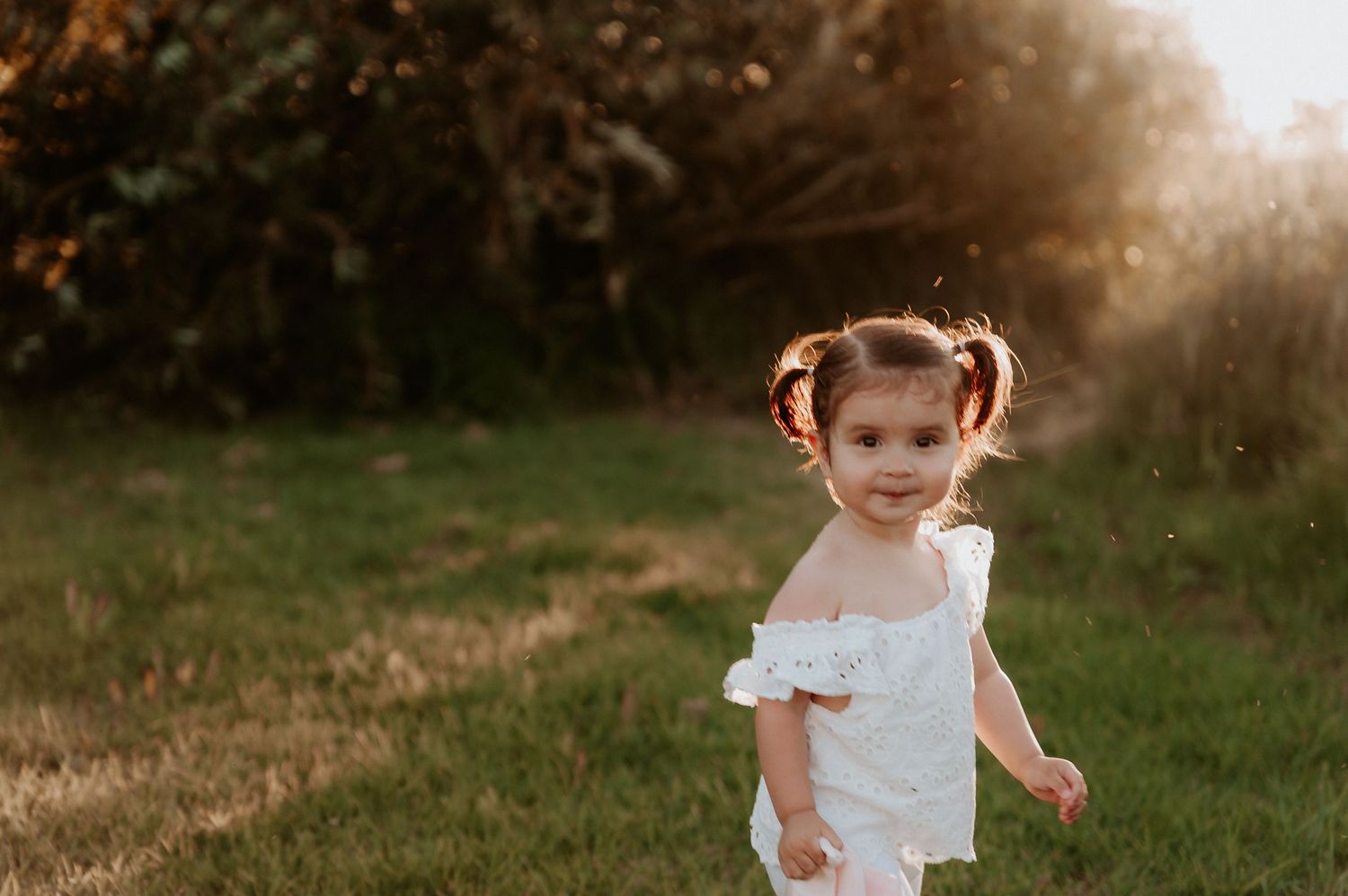 A young child in white clothing walks through tall grass at sunset.
Altona Family Photographer Melbourne