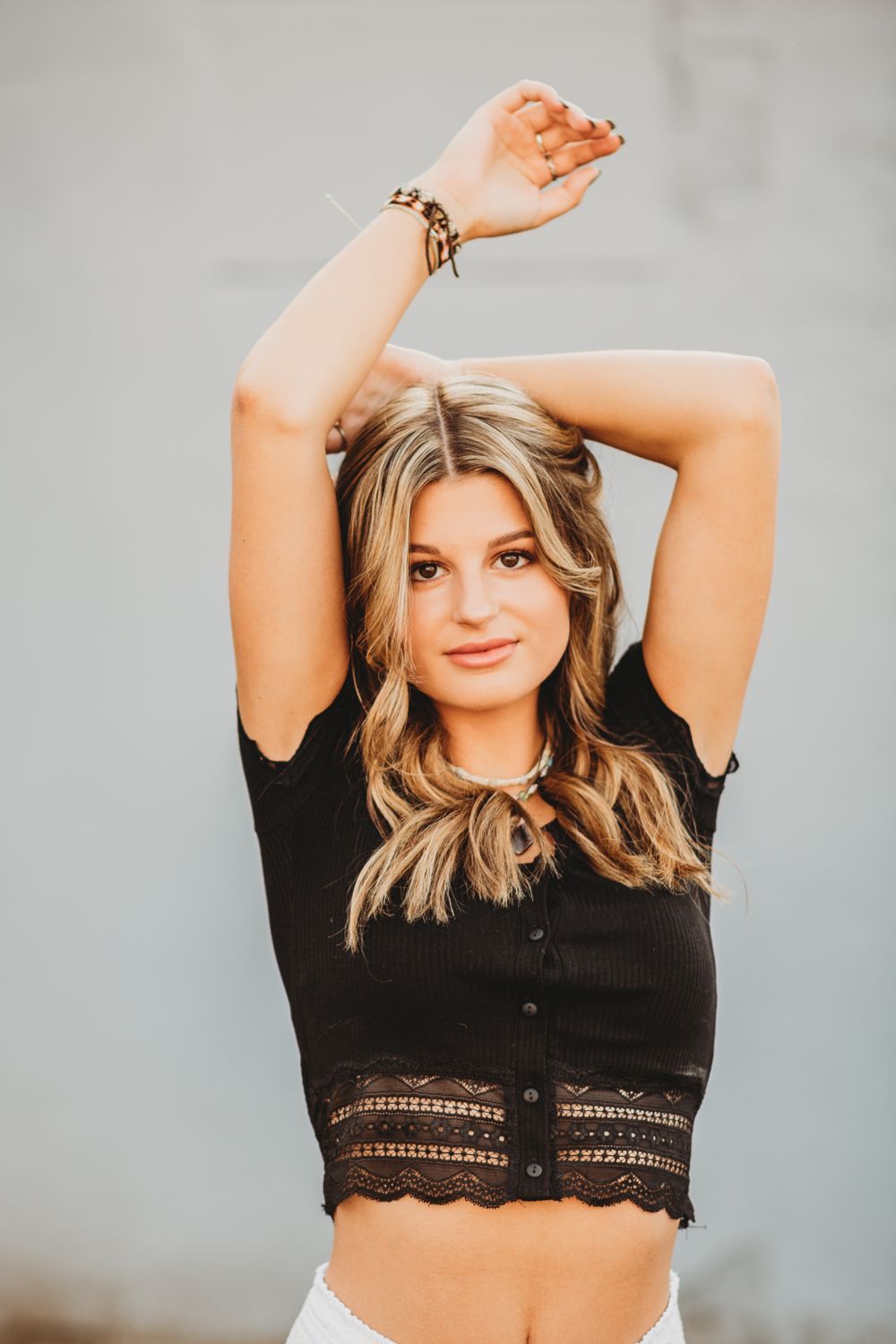 Model poses in a black lace crop top against a plain grey background.