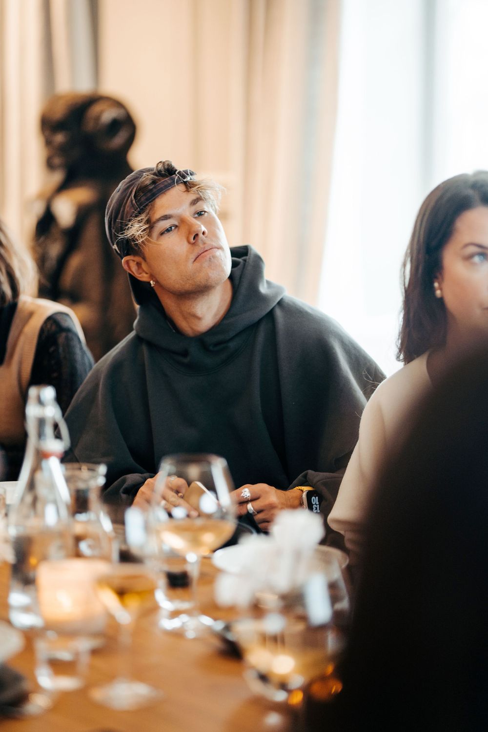 Flera personer samlades runt ett matbord med drinkar och glas i ett väl upplyst rum. Ett Hem Stockholm, Bangerhead, Andreas Wijk