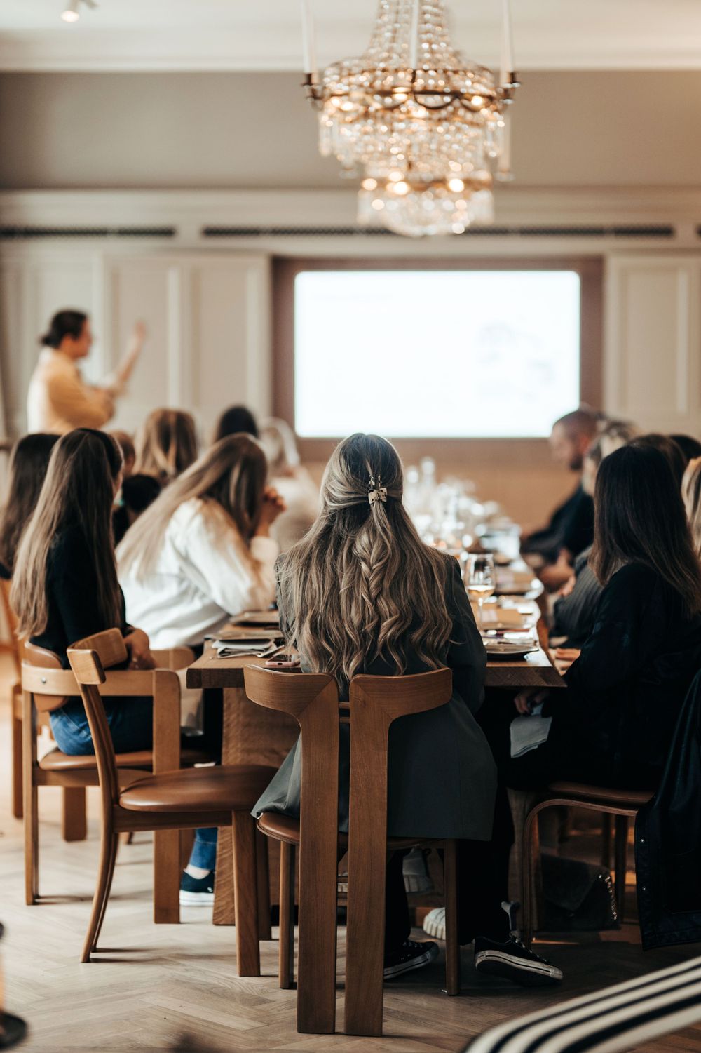 En grupp som deltar i ett seminarium i ett elegant rum med kristallkrona och trämöbler. Ett Hem Stockholm, Bangerhead