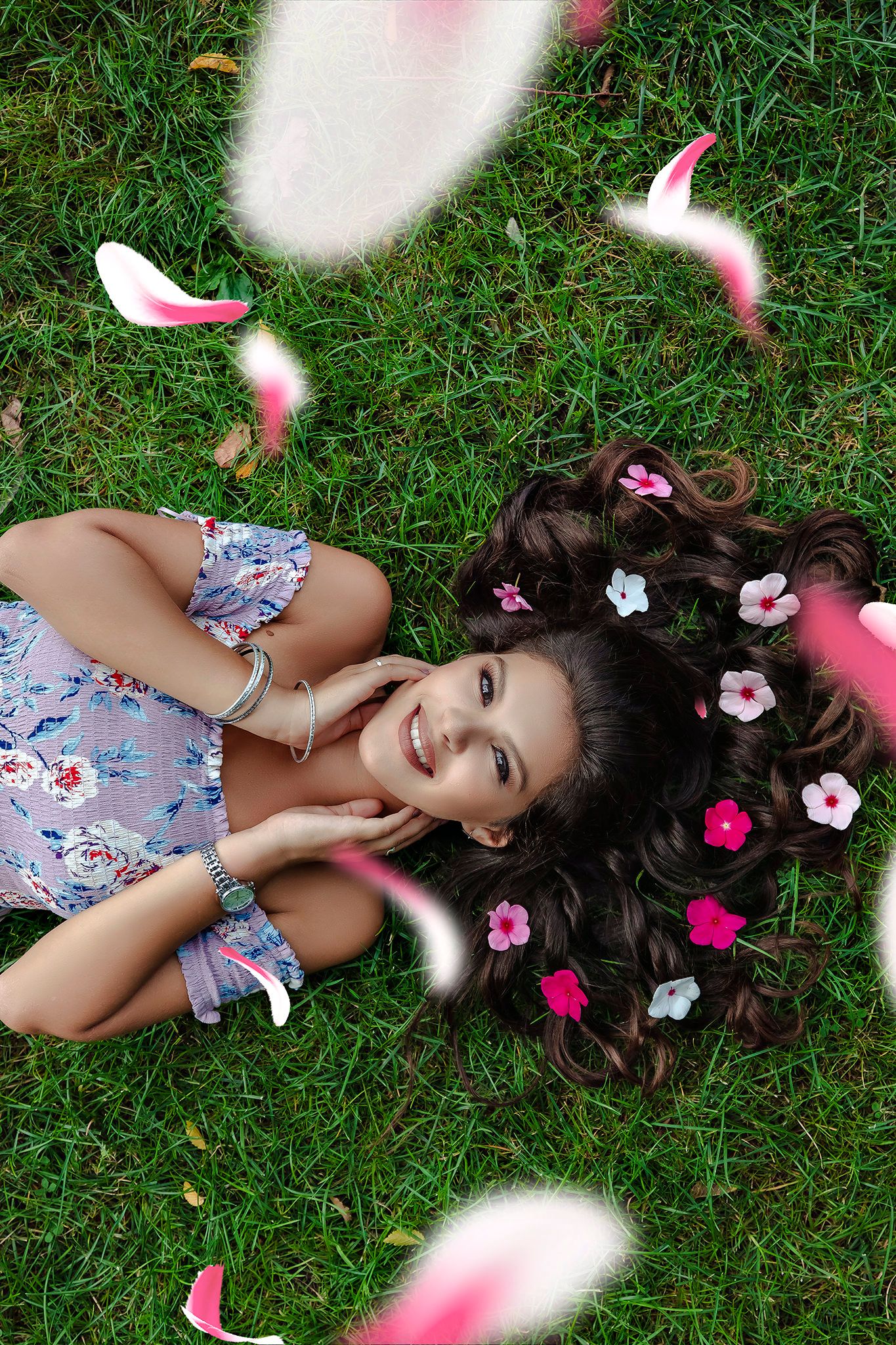 Floral dress portrait with pink blossoms scattered in grass.