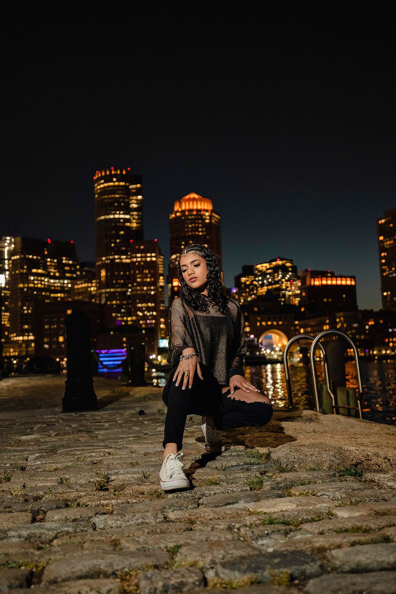 Nighttime urban portrait session with city skyline backdrop.