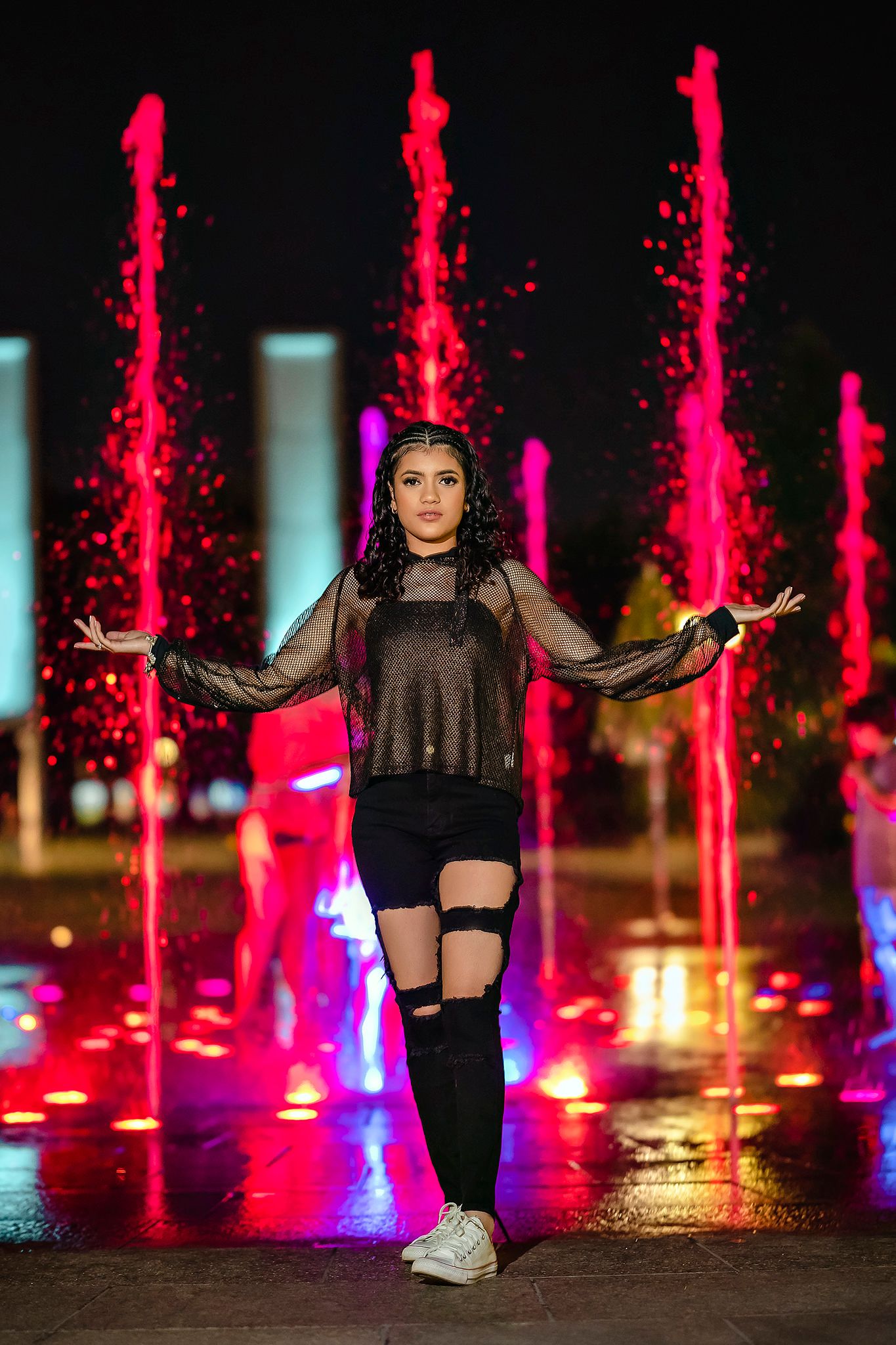Dynamic poses captured by illuminated red fountains at night.