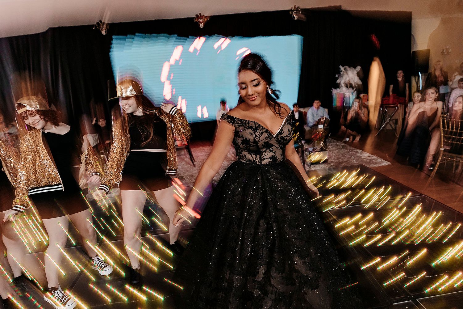 Dancers move energetically on a dance floor with blurred motion effects and golden light streaks during a celebration party.