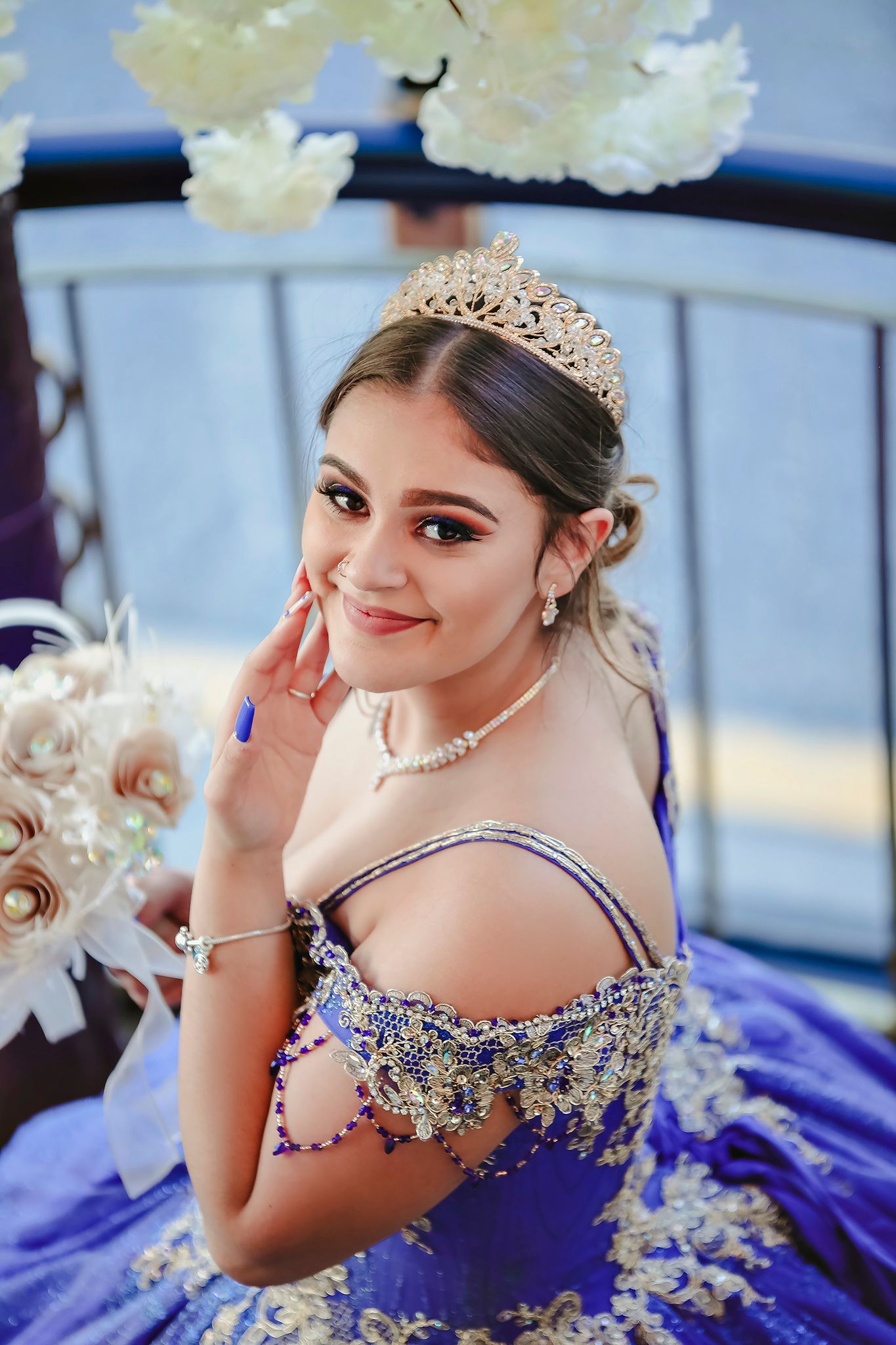 Young woman in sparkling blue quinceañera dress and tiara posing for portraits.