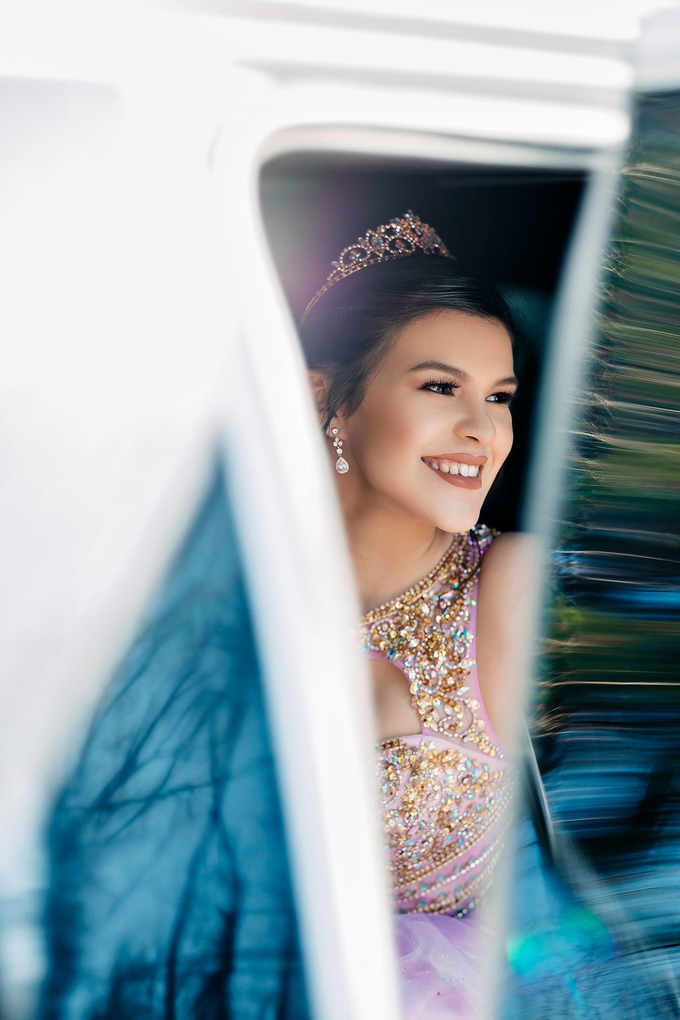 Close-up portrait showing intricate floral embellished dress and smiling expression with blurred background motion effects.