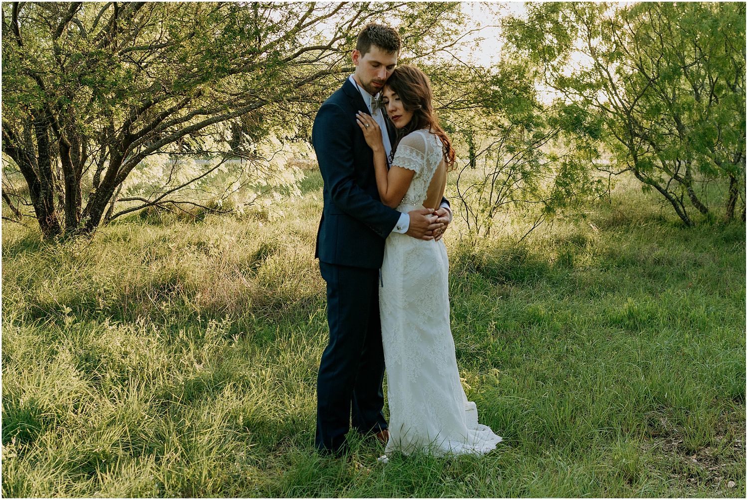 Elegant wedding portrait in natural setting with soft afternoon light filtering through trees.