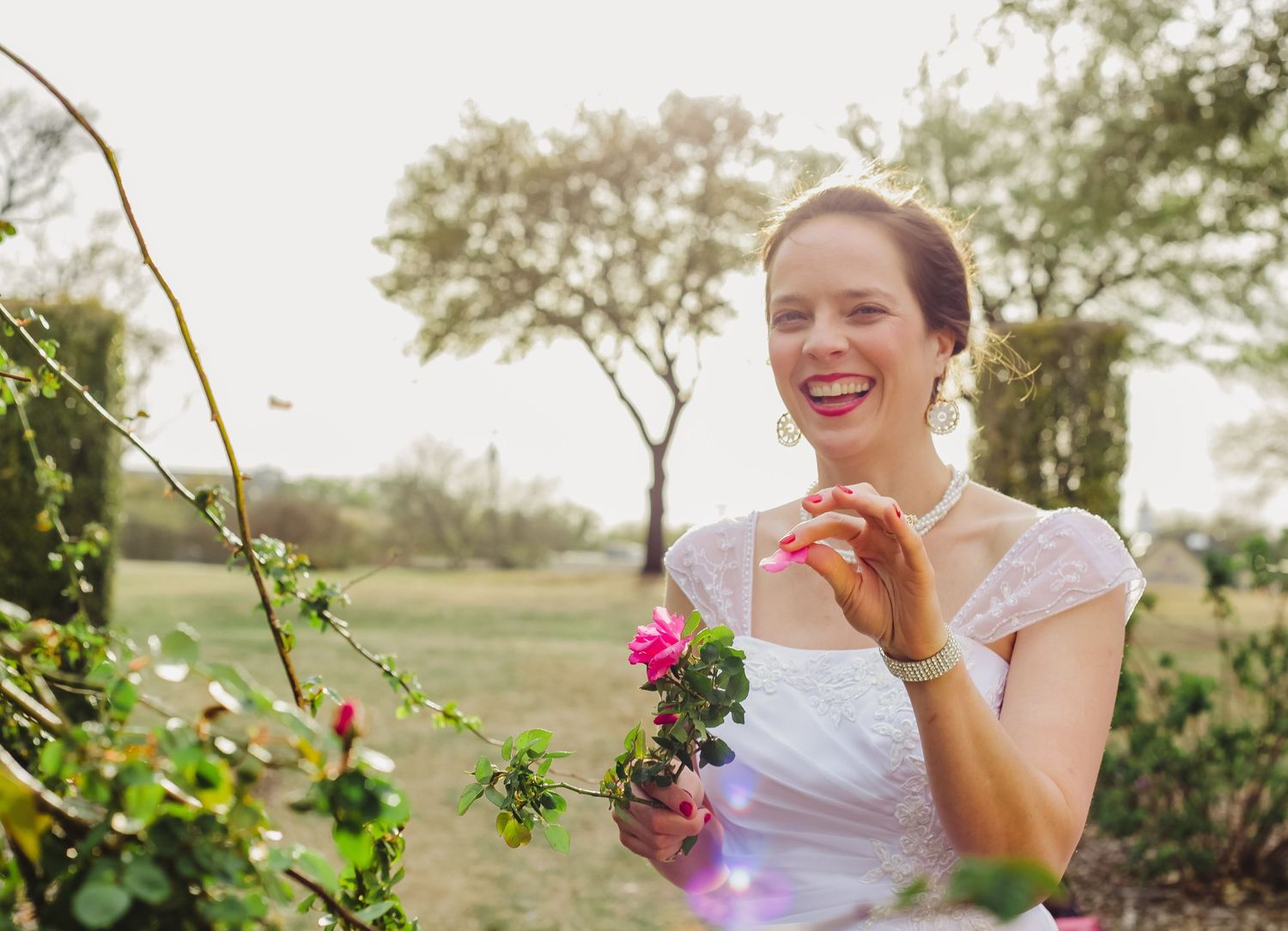 White wedding dress captured in garden setting with flowering vines.