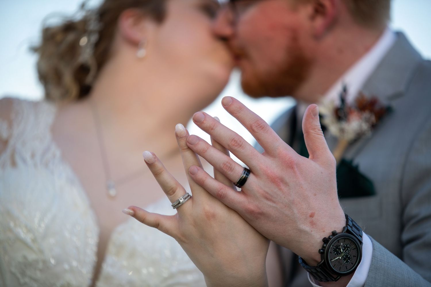 Close-up of newlyweds showing off wedding rings during intimate moment.