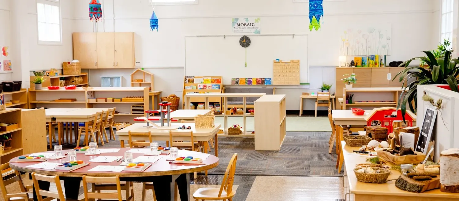 Montessori classroom with wooden furniture, learning materials and natural lighting.