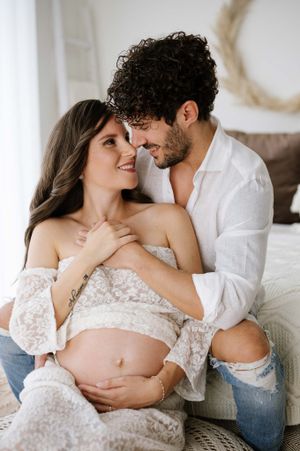 Sweet maternity portrait on couch with bohemian decor and natural window lighting.