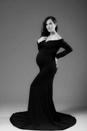 Elegant maternity portrait in floor-length black gown with dramatic train.