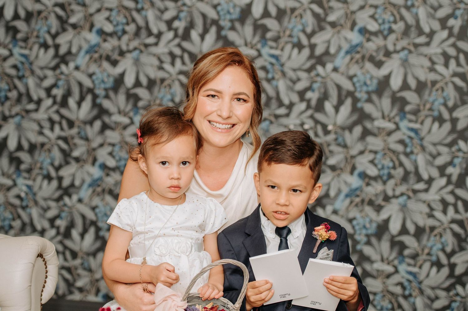 A heartwarming family portrait against a patterned wallpaper background.