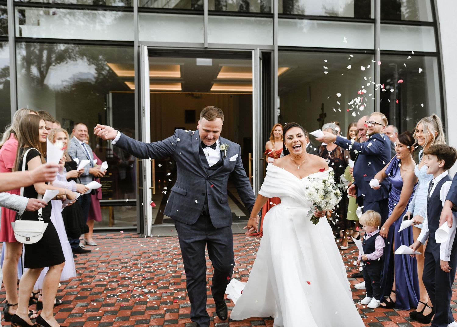 Wedding couple exits venue while guests shower them with confetti.