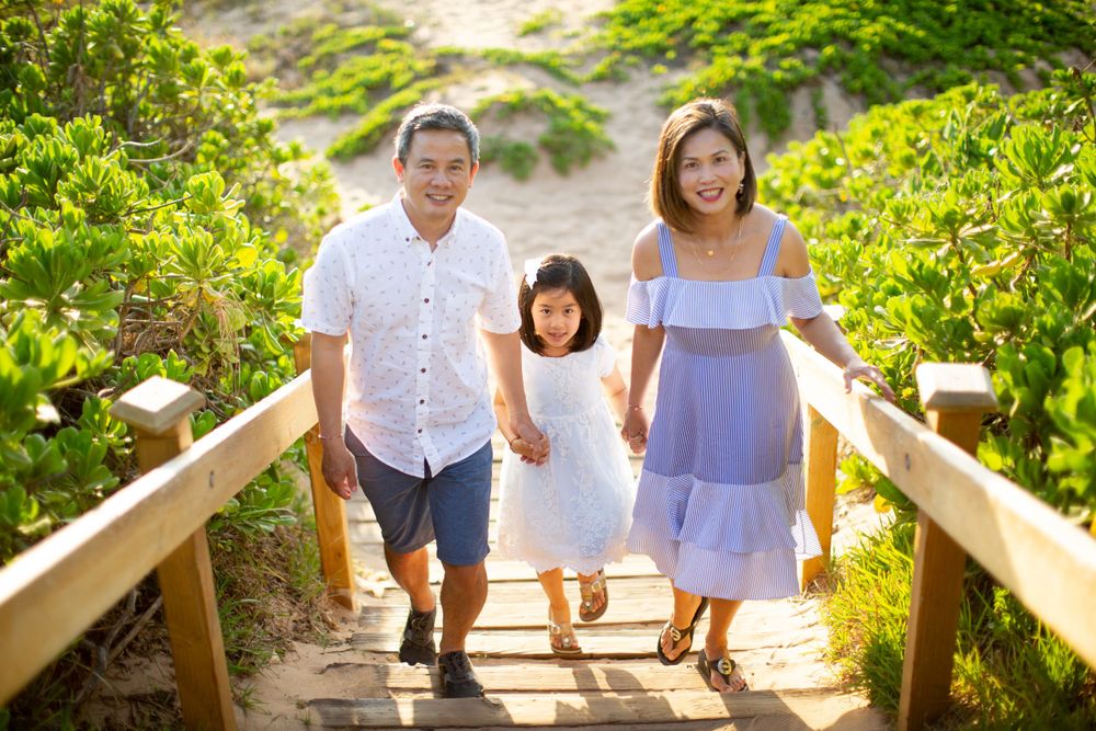 Family walking together on wooden boardwalk surrounded by lush greenery.