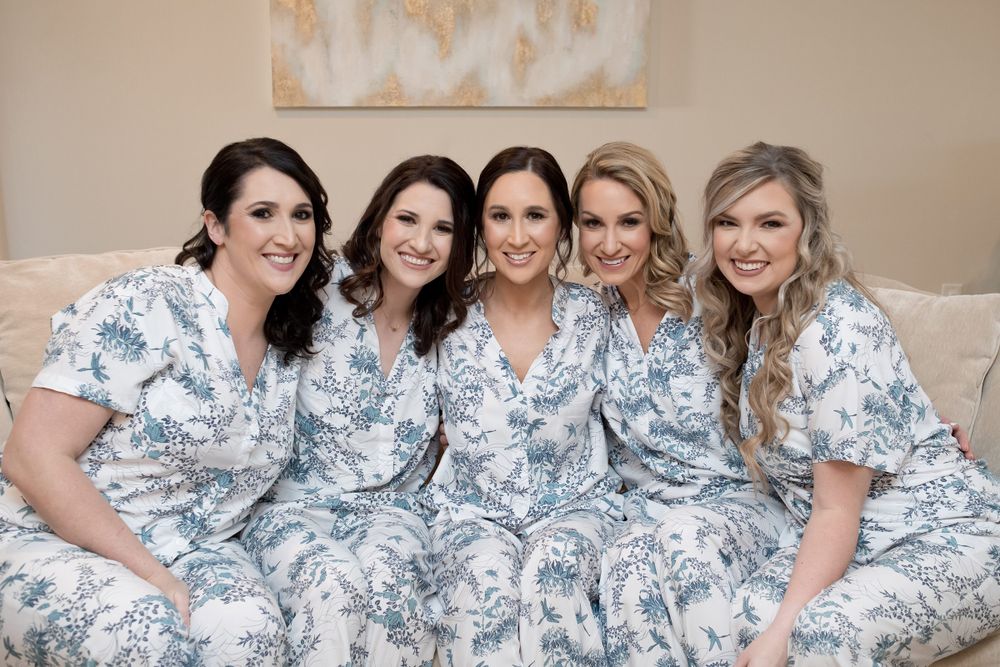 Bridesmaids wearing matching blue floral dresses relaxing together.