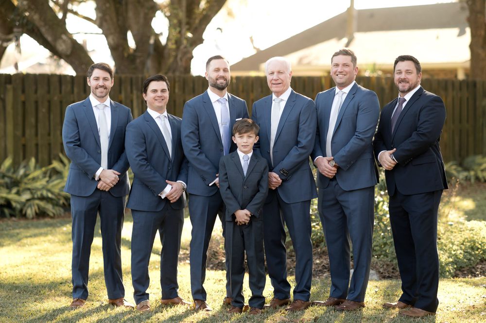 Groomsmen in navy suits posing outdoors at sunset.