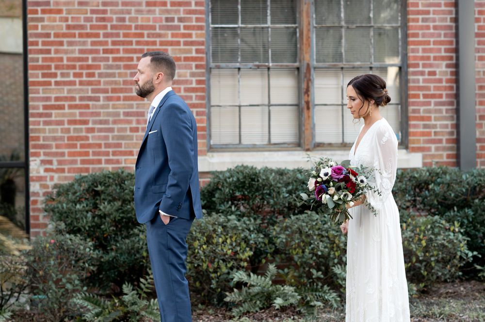 Romantic first look sequence between newlyweds in front of a brick building.
