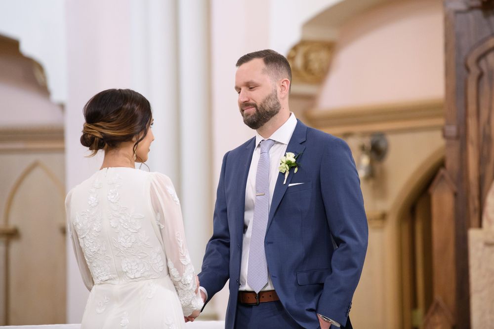 Wedding ceremony in progress at an elegant church with white columns and arches.