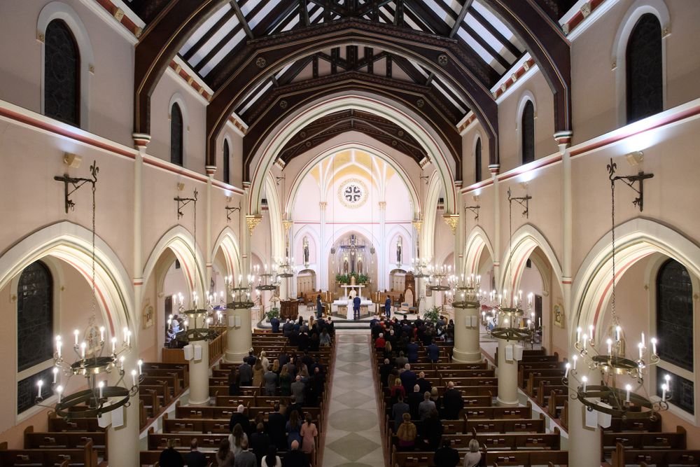 Wide angle view of church sanctuary with vaulted ceiling and hanging chandeliers.