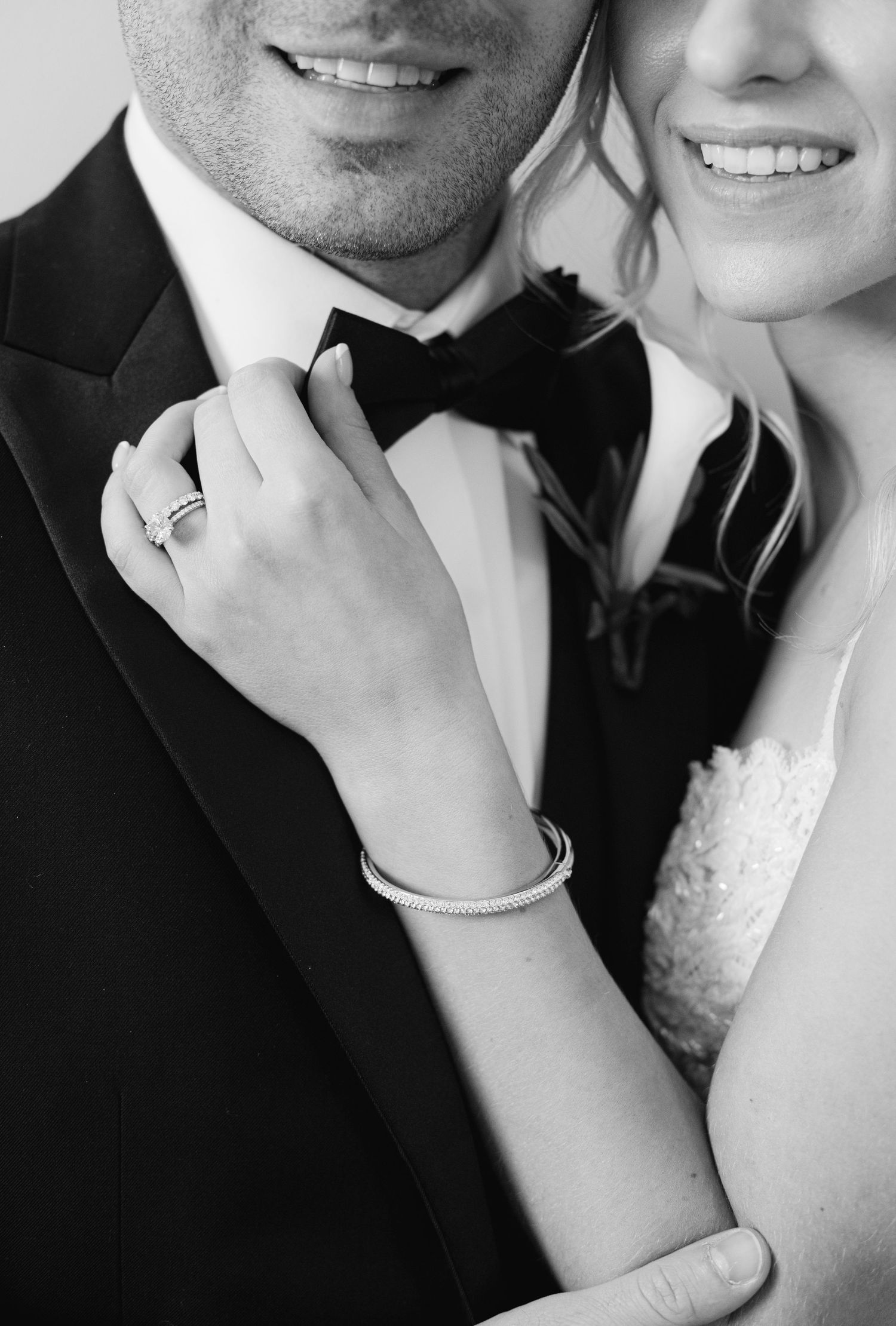 Close-up of elegant black tie and diamond ring details at formal wedding.
