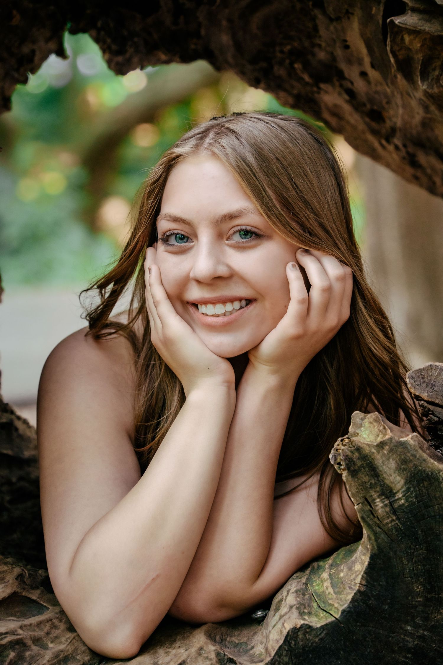 Natural portrait of someone resting in a hollow tree trunk with joyful expression.