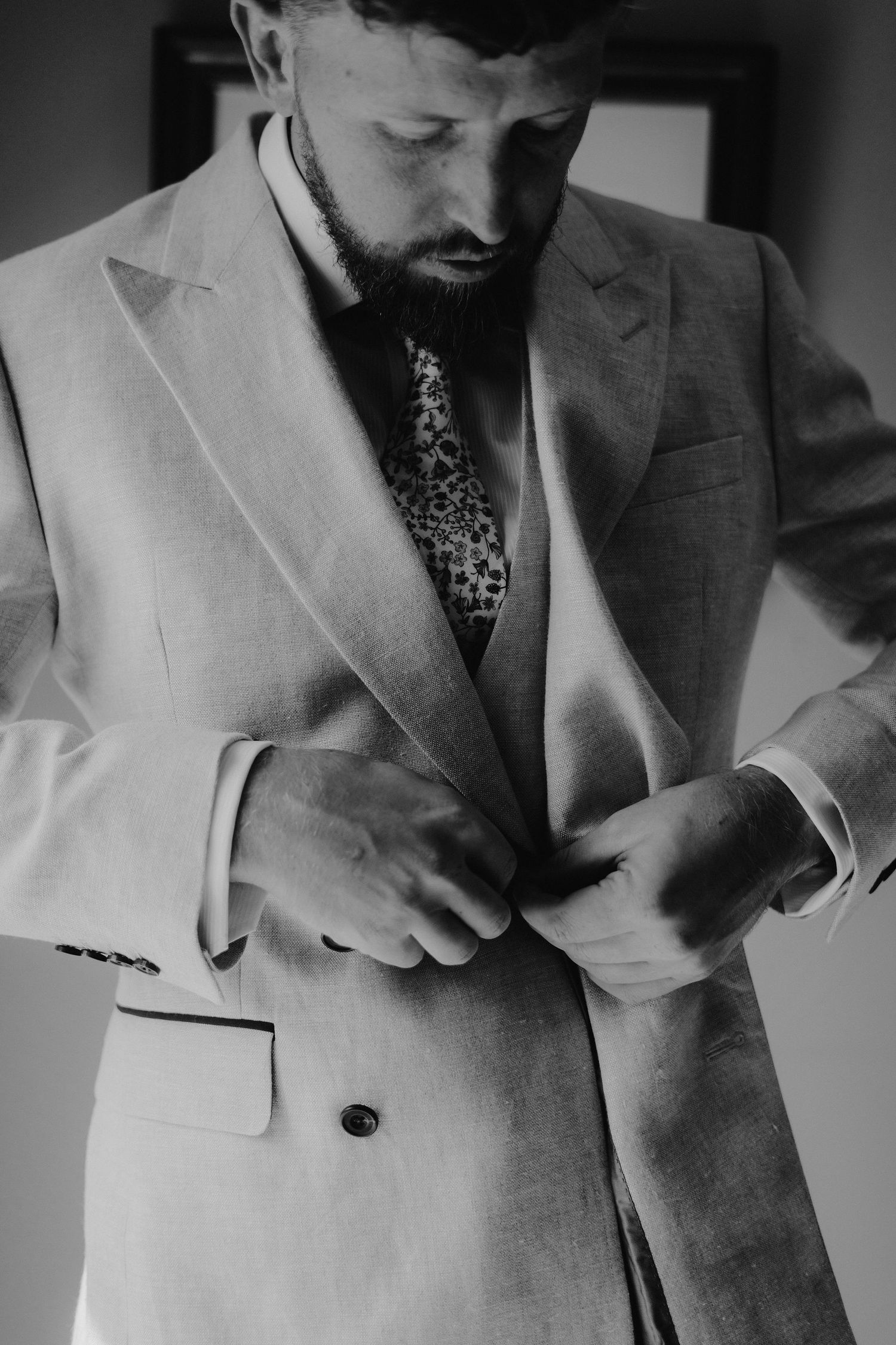 groom fastening jacket button before his wedding ceremony in Oxfordshire