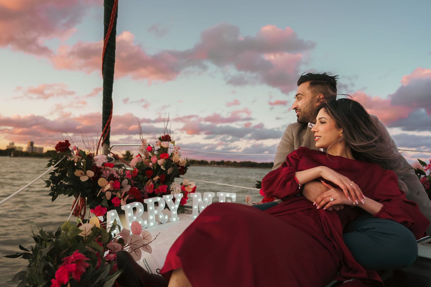 Cotton candy sky, wind's gentle flow. Marry me sign glows as man embraces woman, a proposal embraced by love