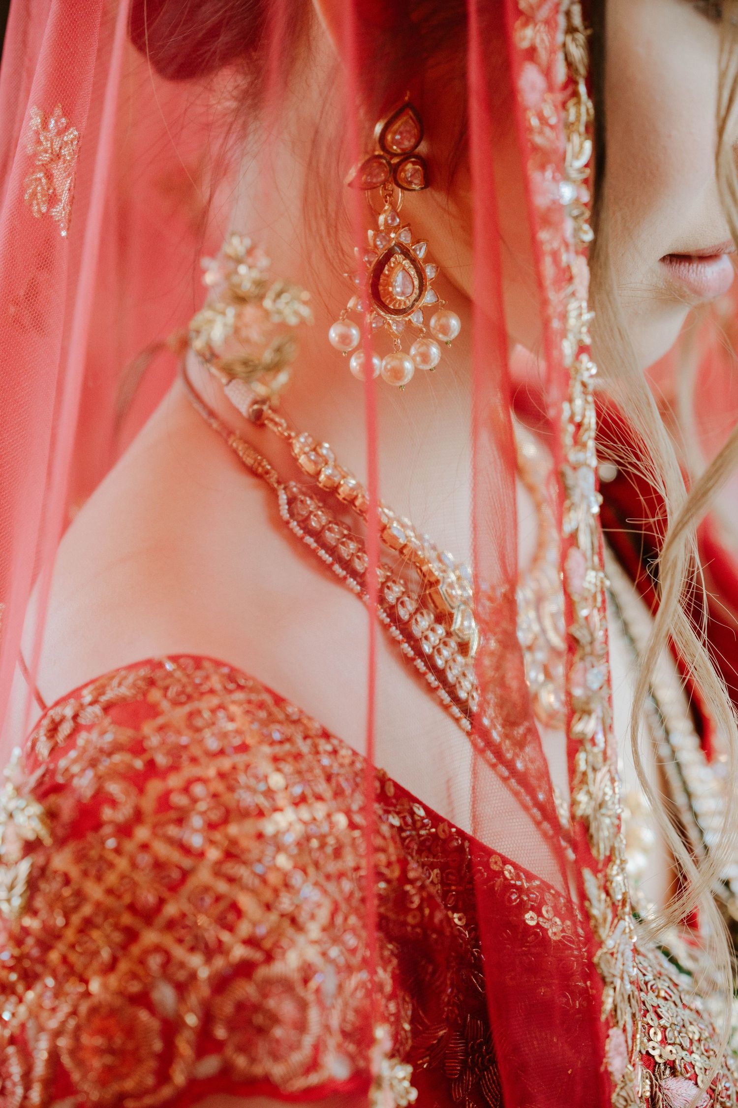 Detailed shot of intricate red and gold embroidery with sheer fabric draping.