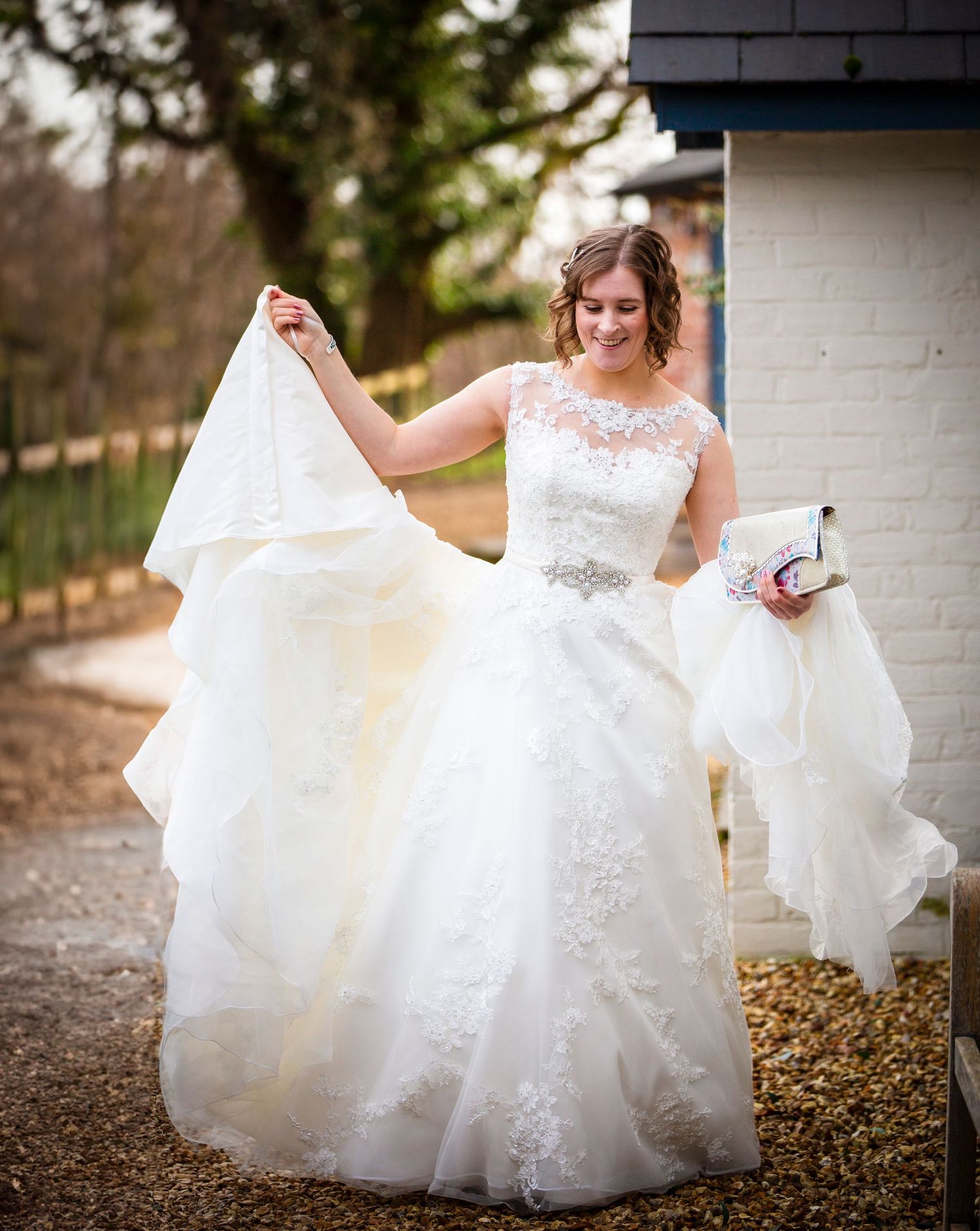 White wedding dress details with lace and tulle fabric flowing in outdoor setting.