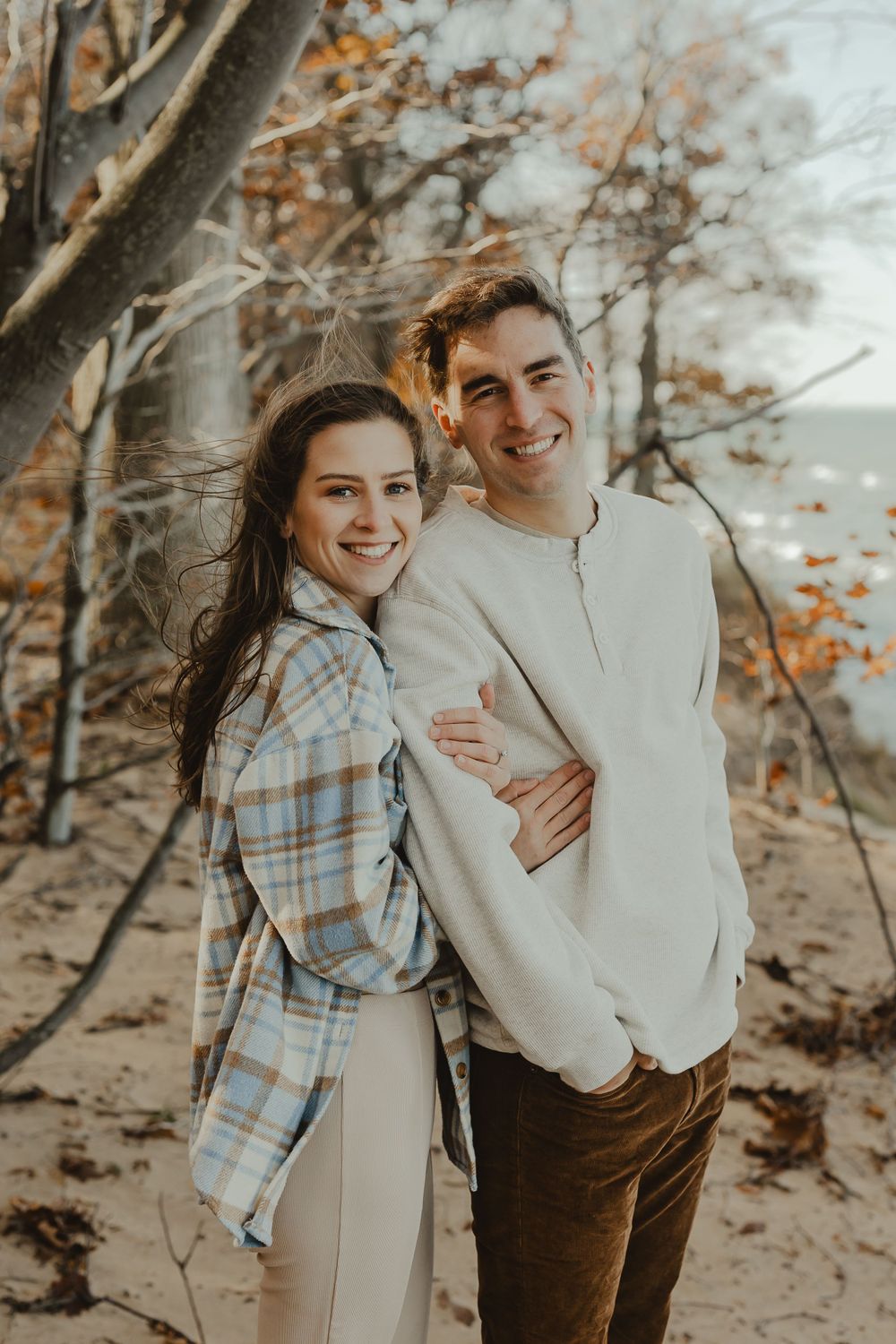 A couple in coordinated outfits sharing a tender moment against a backdrop of fall colors.
