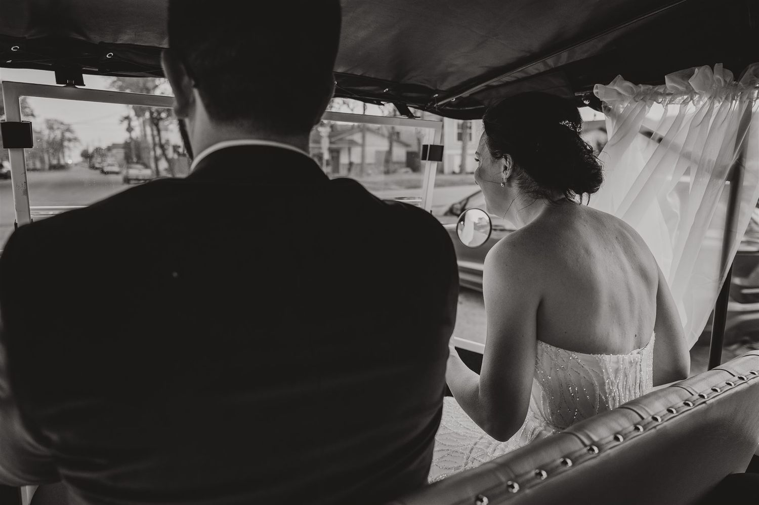 Black and white photo capturing a couple riding in a wedding car together.