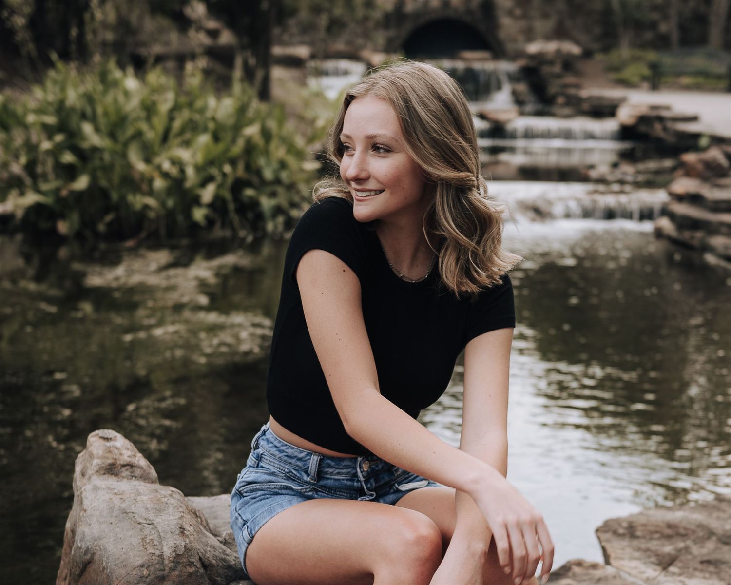 A casual portrait at a scenic waterfall garden with stone landscaping.