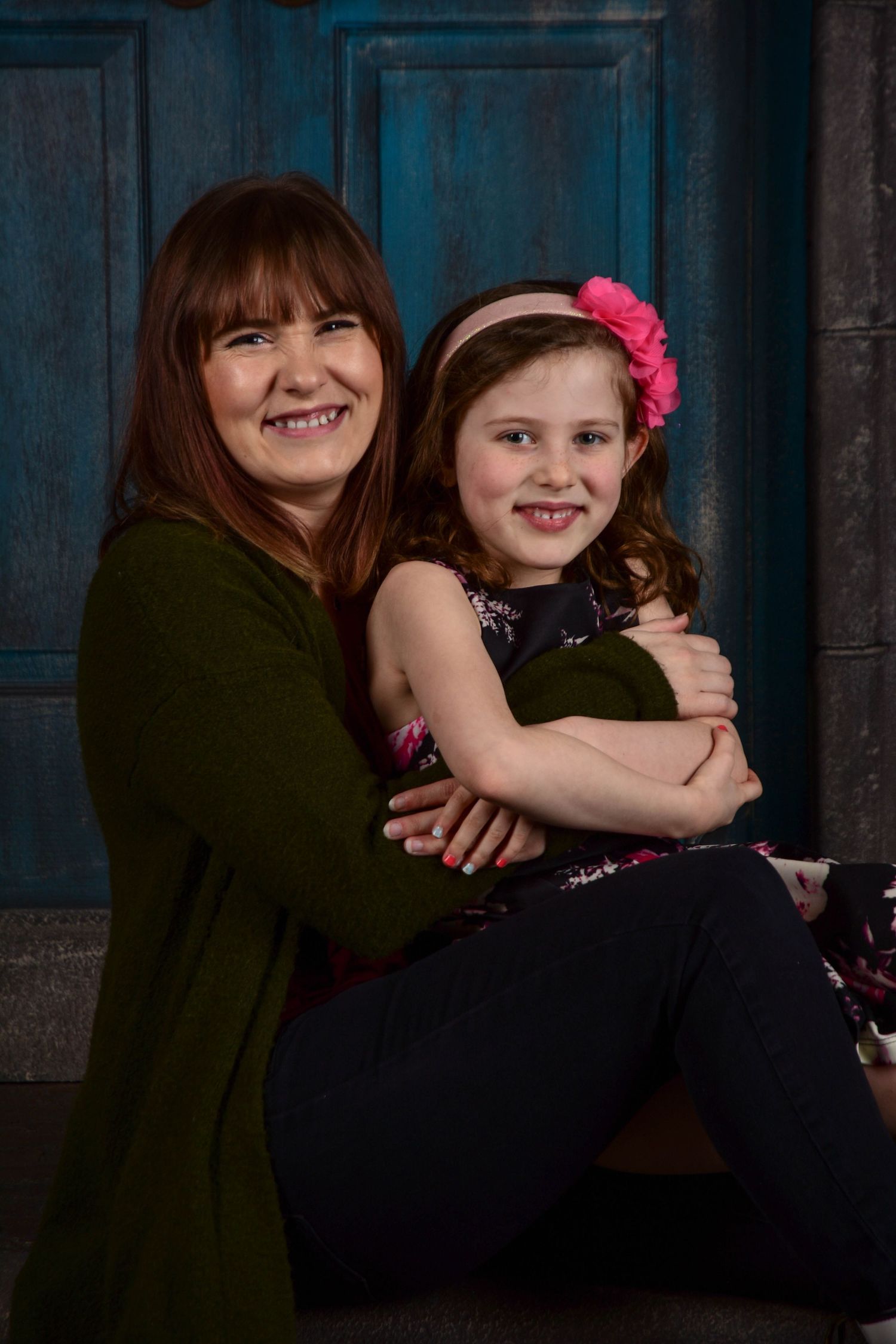 Intimate family portrait session against dark blue backdrop.