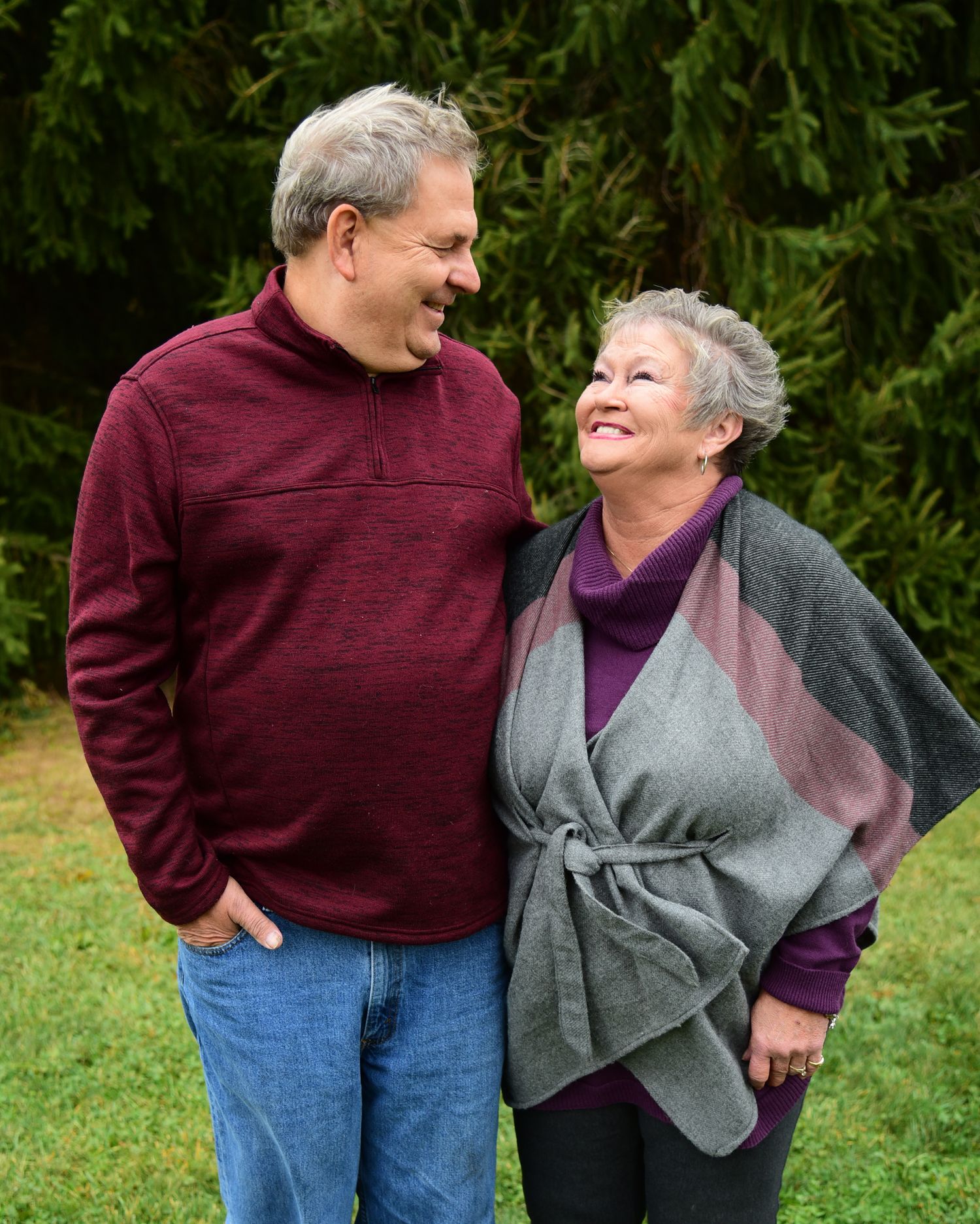 Couple in burgundy and gray casual wear share affectionate moments outdoors.
