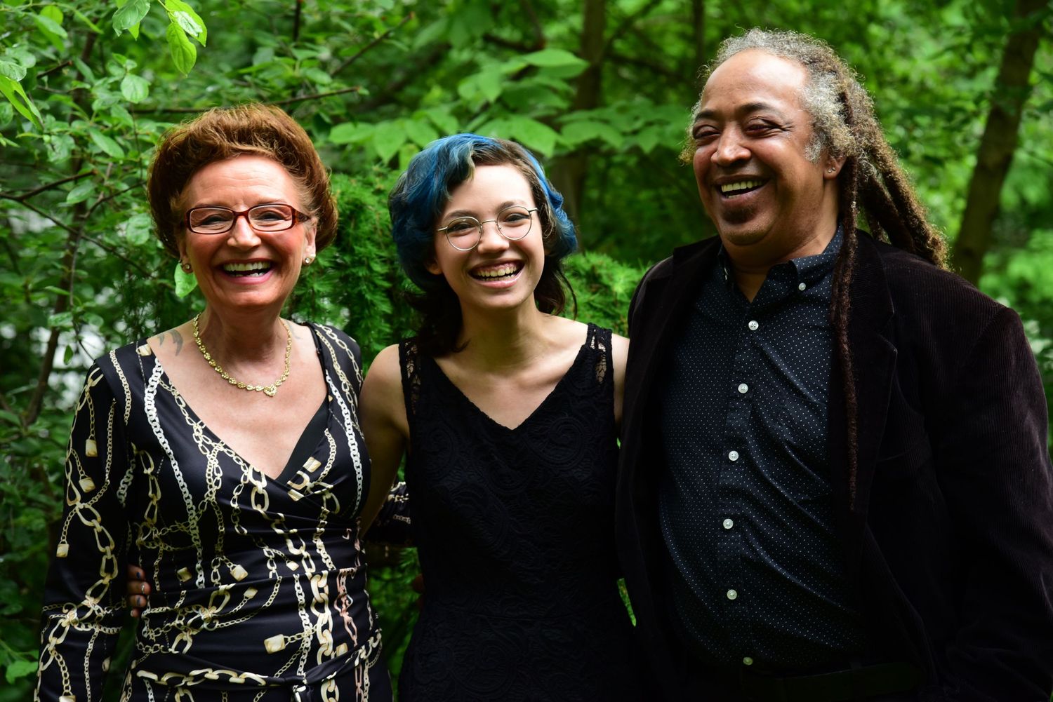 Group photo in a lush green outdoor setting with people smiling and enjoying themselves.