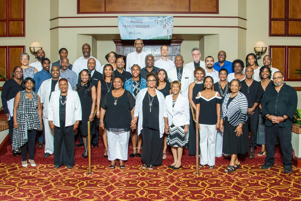 Large group photo of formally dressed people posing in an elegant indoor venue with ornate decor.