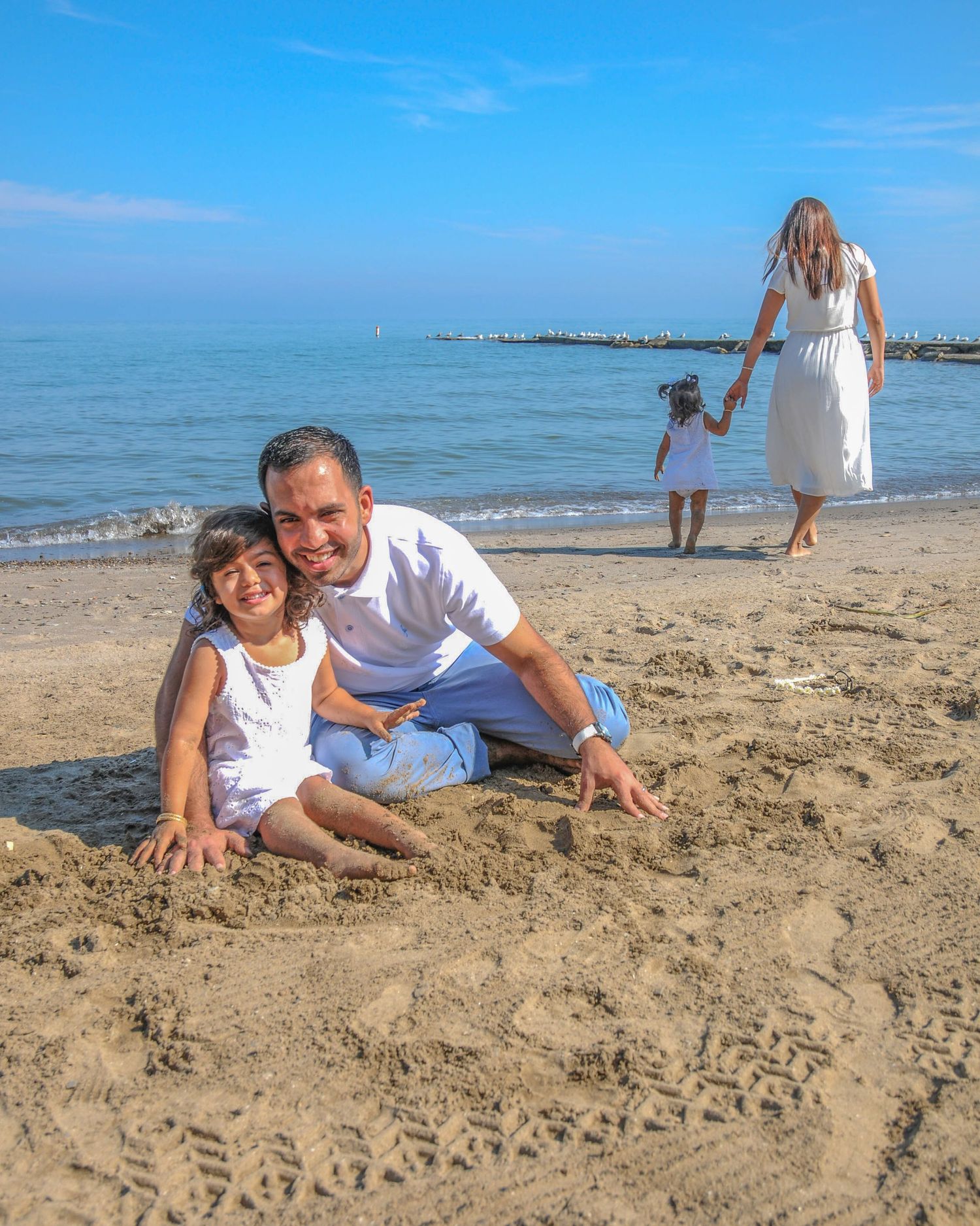 Happy couple lying on sandy beach during sunset photoshoot.