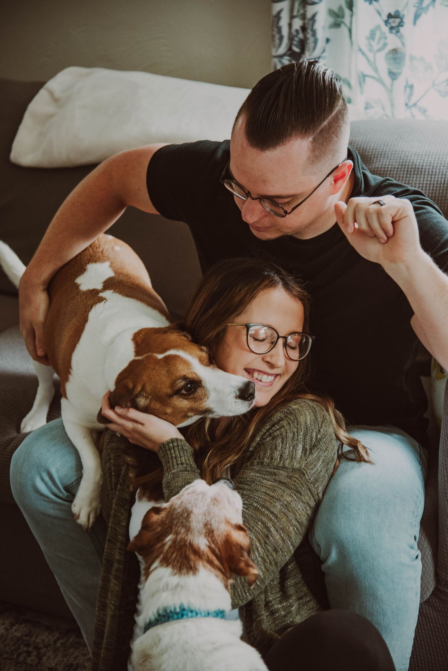 Cozy couple cuddling with their Jack Russell terrier dog on a comfortable couch.