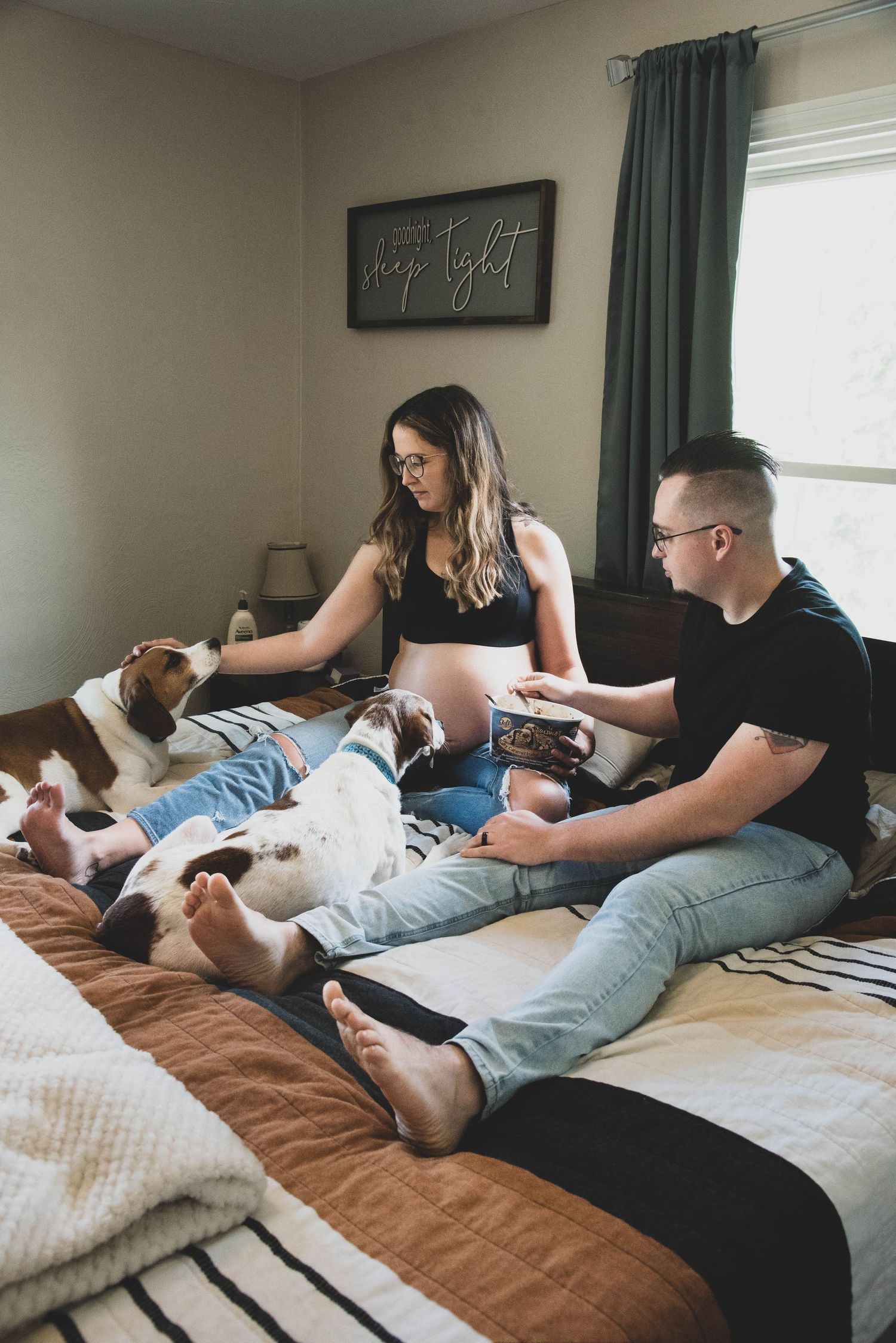 Couple relaxing on bed with their dog while looking at photos.