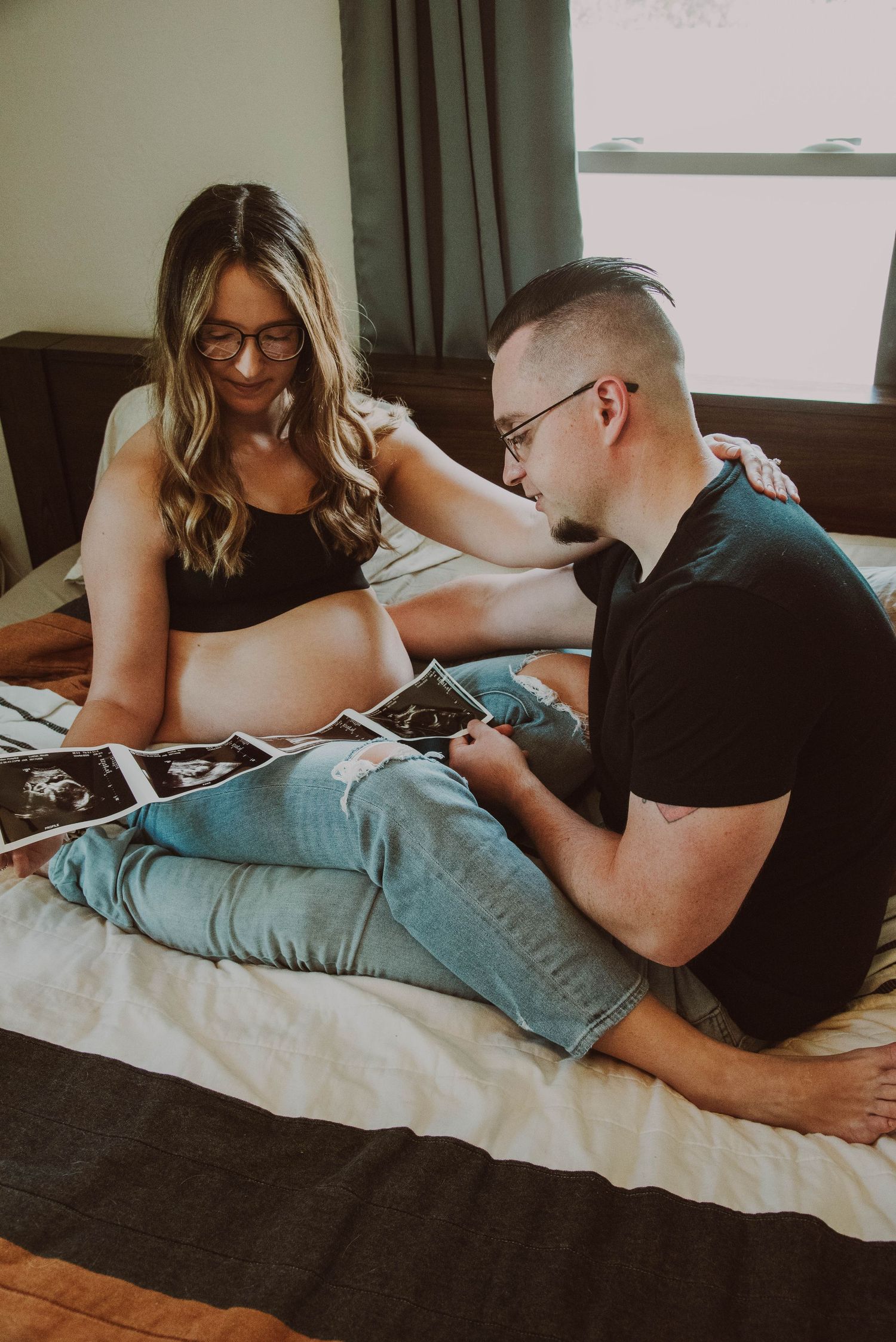 Couple looking at ultrasound photos while relaxing on bed.