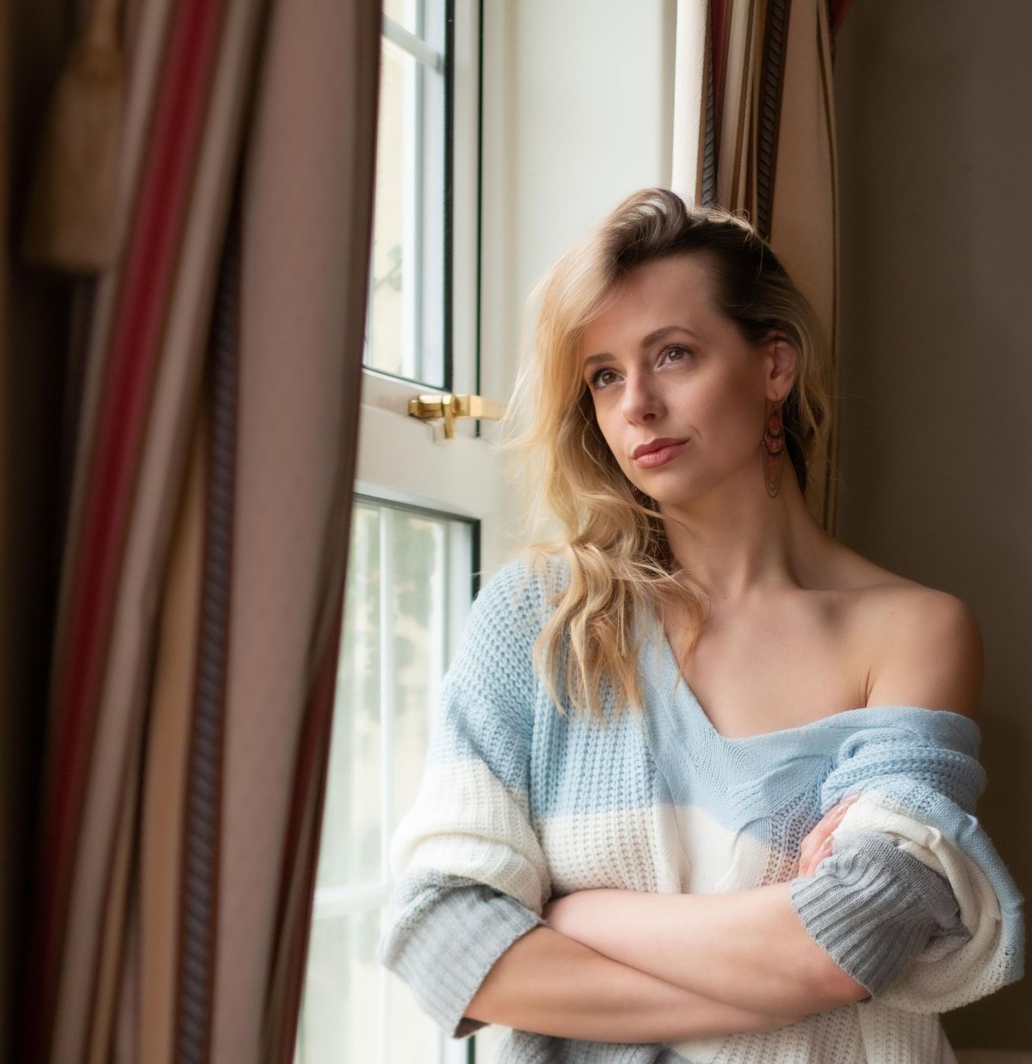 Casual portrait by window wearing striped sweater with natural lighting.